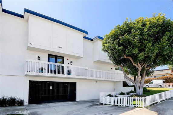 Front view of a white building with a balcony and garage entrance.