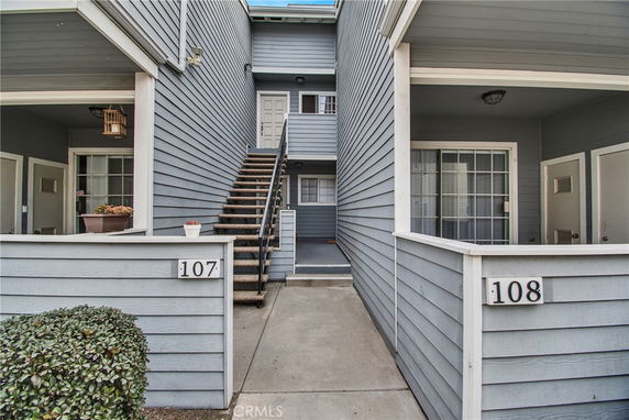 Exterior view of a two-story residential building with stairs leading to upper units.