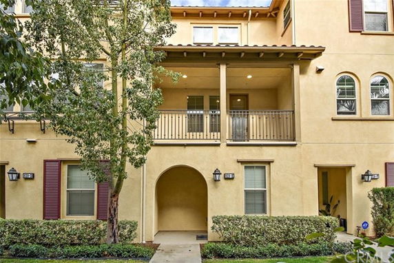 Front view of a multi-story building with balconies and arched entryway.