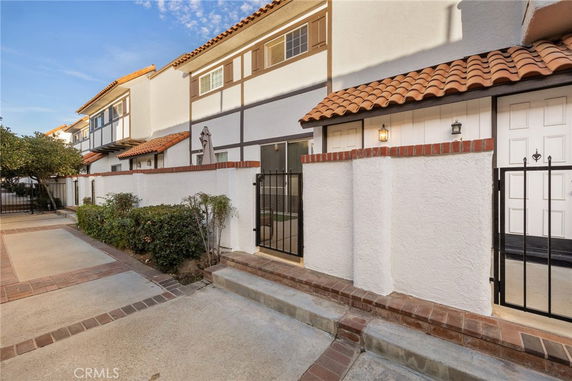 Front view of a two-story house with a gated entrance and tiled roof.