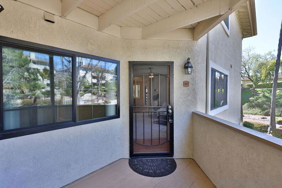 Front view of a house entrance with a screen door and surrounding windows.