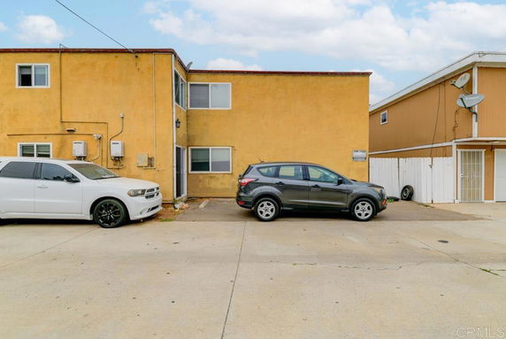 Outdoor parking area in front of a two-story building.