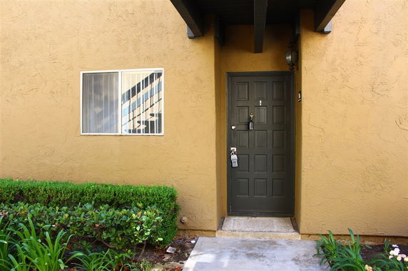 Front entry view of a building with a wooden door and adjacent window.