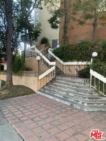 Front view of a building with stairs leading up to the entrance and a sloped pathway.