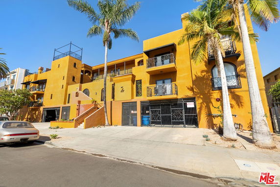 Front view of a multi-story building with a vibrant yellow facade and balconies.