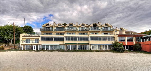 Front view of a multi-story beachfront building with multiple balconies and large windows.