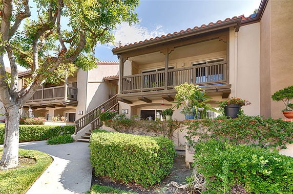 Front view of a multi-story residential building with balconies and surrounding greenery.