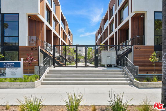 Front view of modern townhomes with wooden accents and gated entrance.