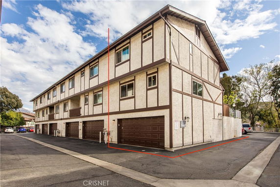 Front view of a three-story residential building with multiple garages at the ground level.