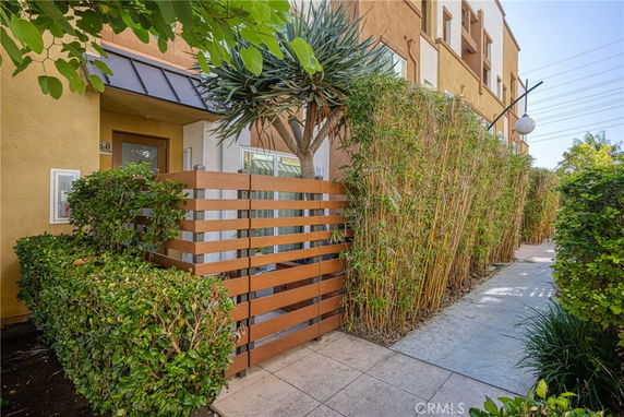 Front view of a multi-story building with a wooden fence and garden area.