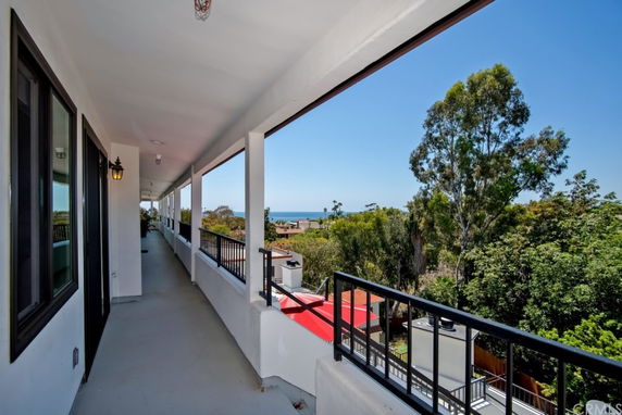 Outdoor corridor of a building with a view of trees and distant ocean.