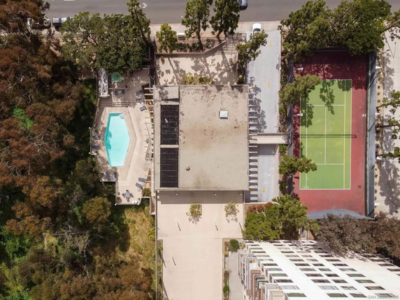 Aerial view of a building with a rooftop, swimming pool, and tennis court.