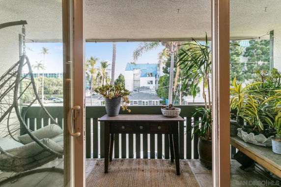 View from a balcony overlooking surrounding buildings and palm trees.