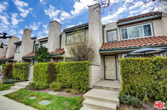 Front view of a row of two-story houses with tile roofs and chimneys.