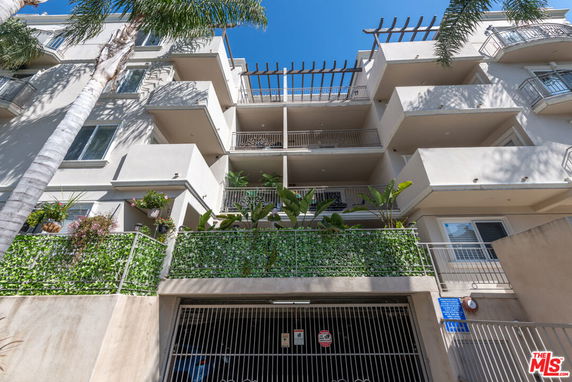 Front view of a multi-story building with balconies and a gated entrance.