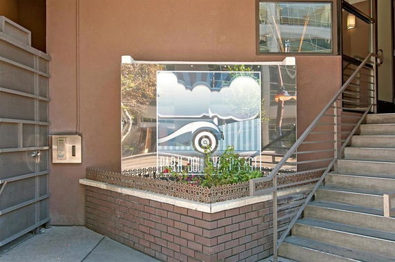 Entrance of a building with steps and a glass panel displaying a logo.