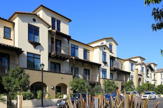 Front view of a multi-story residential building with balconies and tiled roofs.