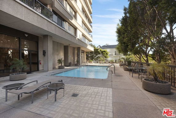Outdoor swimming pool area adjacent to a multi-story building.