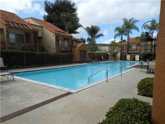 Outdoor swimming pool surrounded by residential buildings with red tile roofs.