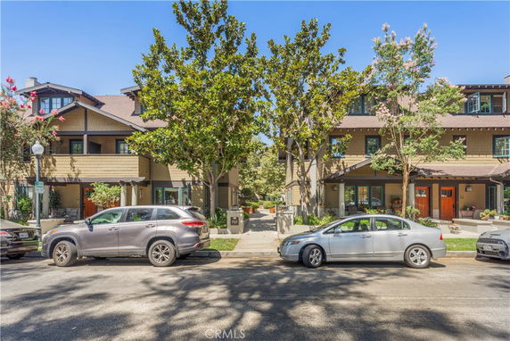 Front view of a multi-story building with trees and parked cars in front.