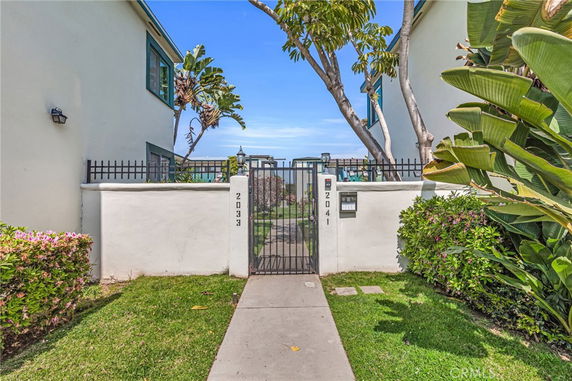 Front entrance of a building with a gated walkway and surrounding greenery