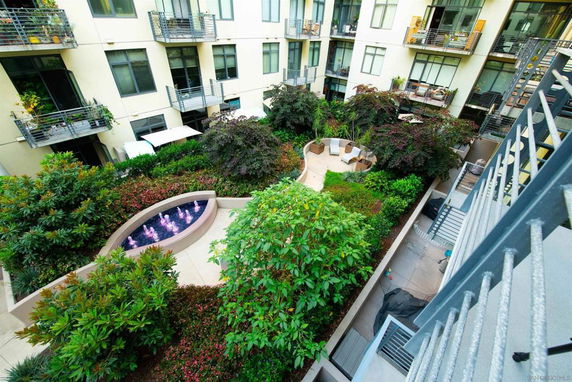 View of a courtyard surrounded by apartment buildings with gardens and seating areas.