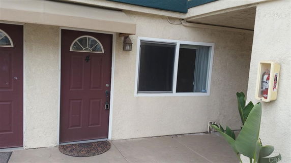 Front view of a building entrance with a maroon door and window.