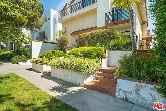 Front view of a multi-story house with balconies and landscaped entrance.