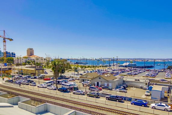 View of a harbor area with parking lots, buildings, and a water body in the background.