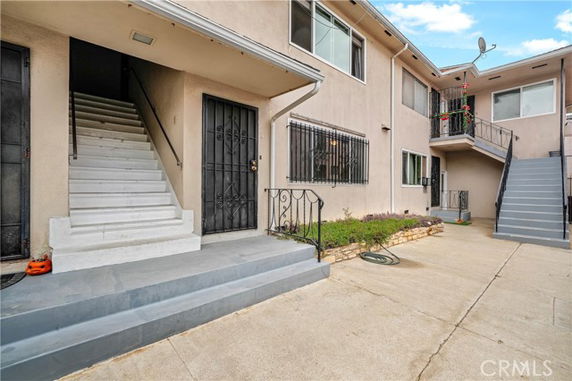 Front view of a multi-story apartment building with external staircases and entry doors.