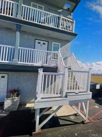 Front view of a multi-story building with white railings and balconies.
