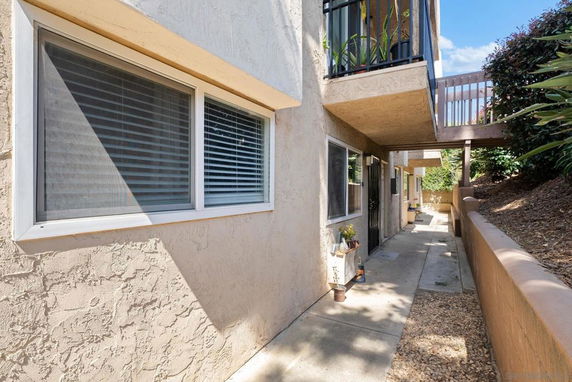 Side view of an apartment building with a walkway, windows, and a small balcony.