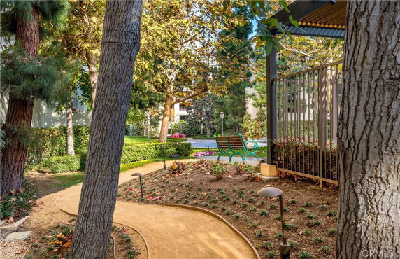 Garden path leading through a landscaped area with trees and benches.