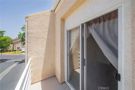 View from a balcony with sliding glass doors, overlooking a residential street.