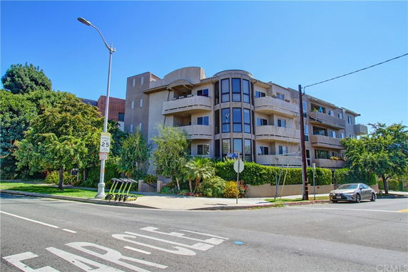 Front view of a multi-story apartment building with balconies and large windows.