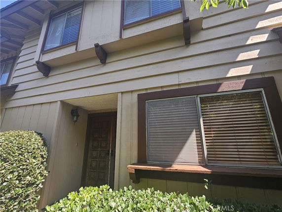 Front view of a two-story house with a wooden exterior and large windows.