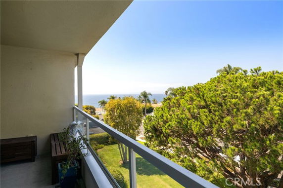 Balcony view overlooking trees and the ocean in the distance.