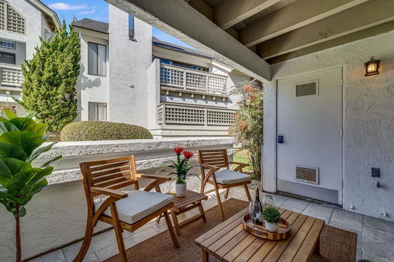 View of a residential building with outdoor seating area and green landscaping.