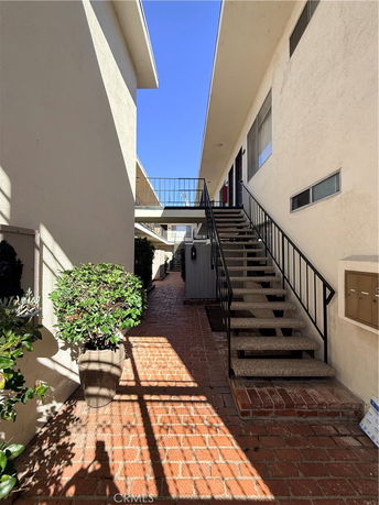 Stairway and walkway of a multi-story building with brick flooring.
