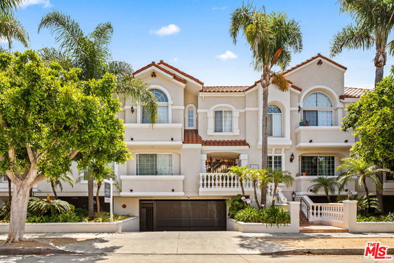 Front view of a multi-story house with a decorative balcony and arched windows.