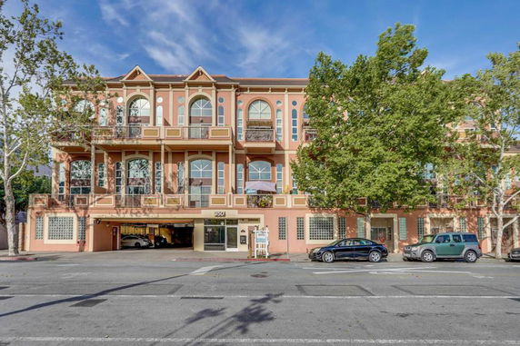 Front view of a three-story building with balconies and large arched windows.