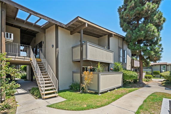 Front view of a two-story apartment building with balconies and outdoor stairs.