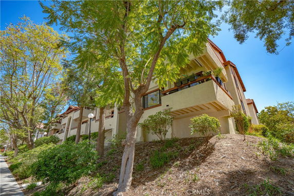 Front view of a multi-story residential building with balconies and trees.