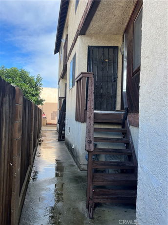 Side view of a two-story house with a wooden staircase and metal door.
