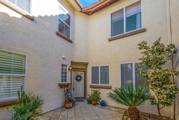 Front view of a house with a courtyard entrance and windows on the upper and lower levels.