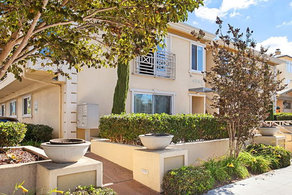 Front view of a two-story building with balconies and landscaped entrance.