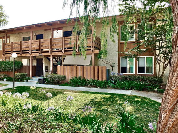Front view of a two-story residential building with wooden balcony and entryway.