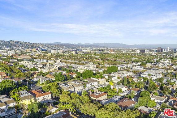 Panoramic view of a cityscape with buildings, trees, and hills in the distance.