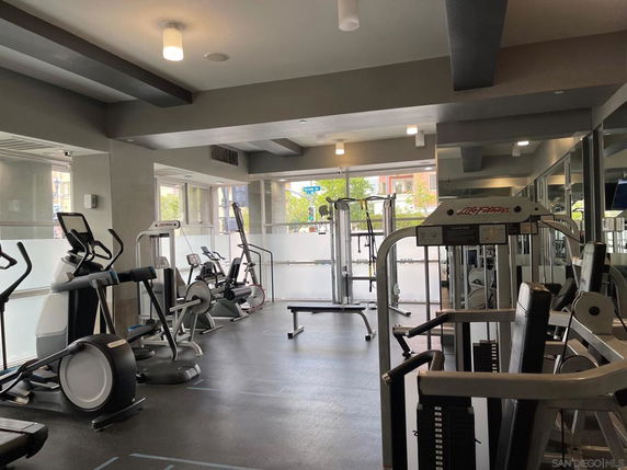 Indoor gym area with various exercise equipment and large windows.