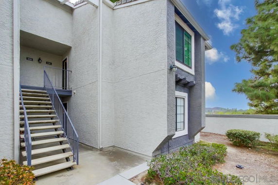 Front view of a two-story building with exterior stairs leading to an upper unit entrance.